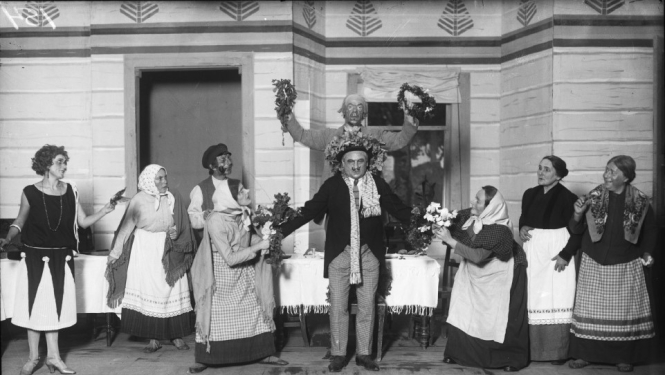 Melnbalta bilde, Aina no A. Saulīša komēdijas “Inteliģenti” uzveduma Nacionālā teātra aktieru izpildījumā. No kreisās: 1. Anta Klints - Adelīnas lomā, 6. Alfrēds Amtmanis-Briedītis - Fēliksa Šmigas lomā, 8. Berta Rūmniece - Vēsmiņas mātes lomā, 9. Ella Jēkobsone - Salmienes lomā. Rīga, 1925.gads. Autors nav zināms. Latvijas Valsts kinofotofonodokumentu arhīvs