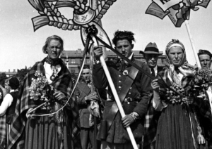 Melnbalta bilde no izstādes "Dziesmu spēks" - kadrs no gājiena, uzraksti "Kurzeme", "Kandava" kolonnas sākums