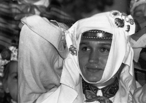 Melnbalta bilde no izstādes "Dziesmas spēks", svētku dalībnieces portrets, sievas galvas rota - galvauts, sasprausta ar saktām