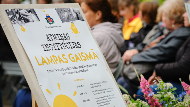 pasākuma baneris, fonā cilvēki