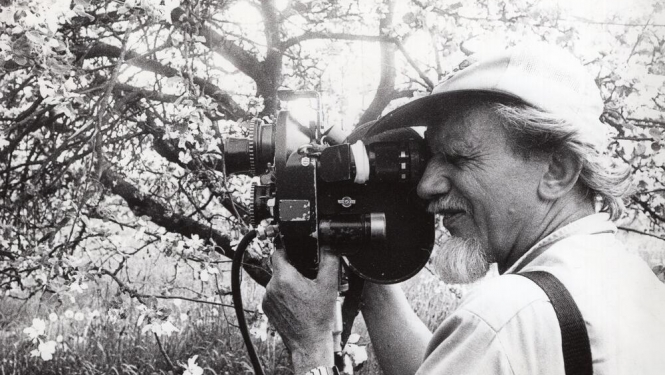 Melnbalta bilde, Kinorežisors, operators Ivars Seleckis filmē ziedošā dārzā. Portrets. Latvija, 20.gs. 70. – 80. gadi. Autors Aivars Dambekalns. Latvijas Valsts kinofotofonodokumentu arhīvs, LNA_KFFDA_F175_2_200