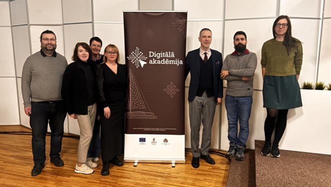 Grupas foto, no kreisās puses stāv četri cilvēki, pa vidu plakāts "Digitālā akadēmija", pa labi trīs cilvēki 