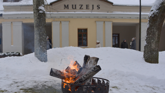 Krāsaina bilde, Balvu muzeja ēka fonā, priekšplāna degošs uzgunskurs