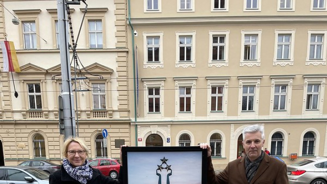 Sievietis un vīrietis pie plakāta ar brīvības pieminekļa attēlu