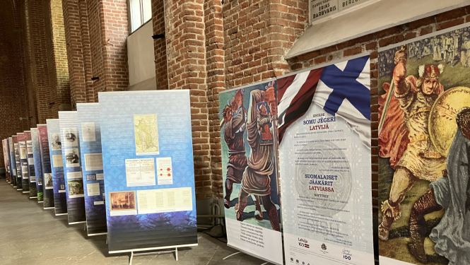 Krāsaina bilde, izstādes stendu rinda un izstādes atklāšanas stendi gar Pēterbaznīcas sienu