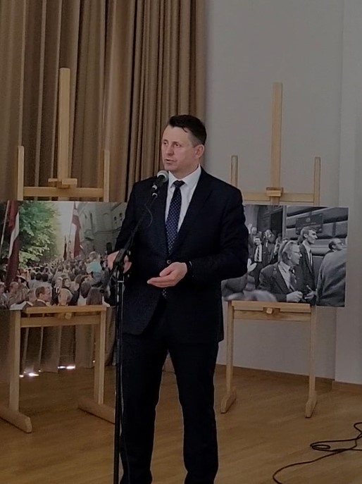 Krāsaina bilde, Balvu novada pašvaldības domes priekšsēdētājs Sergejs Maksimovs atklāj izstādi, fonā izstādes stendi