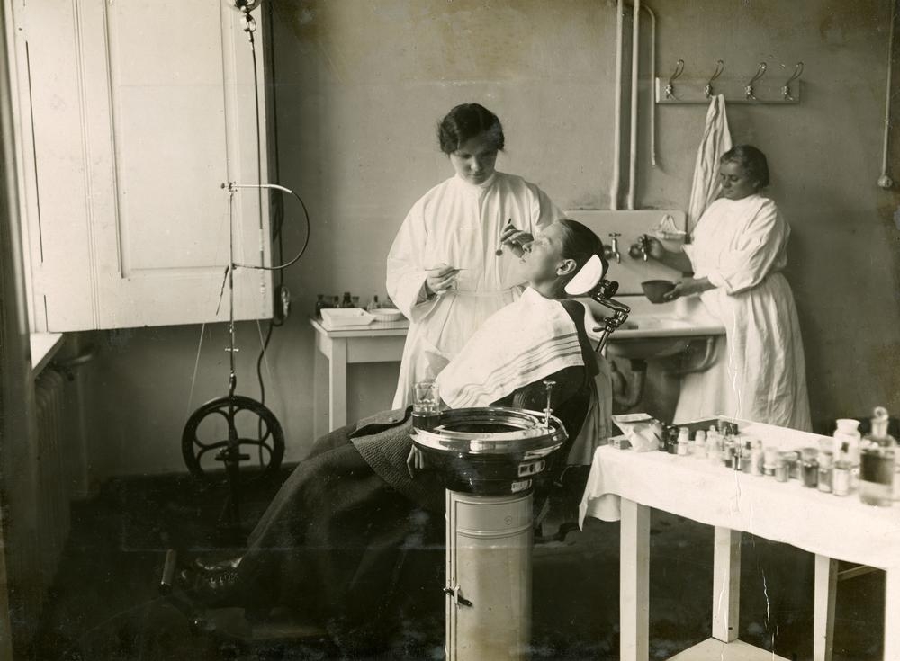 zobārsta kabines, sieviete ārsts, zobārsta palīdz un pacients krēslā