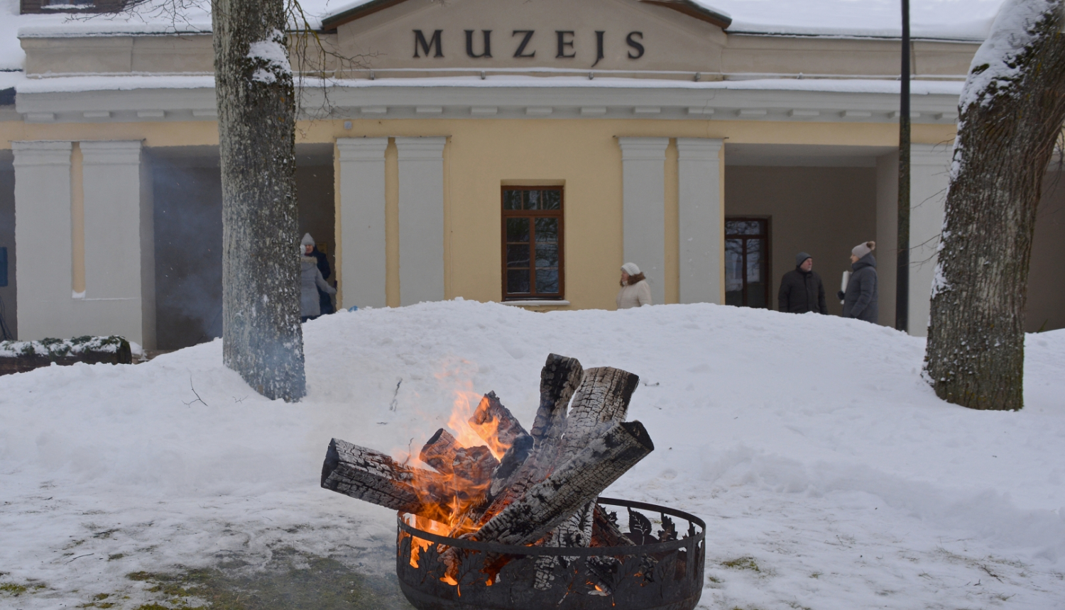 Krāsaina bilde, Balvu muzeja ēka fonā, priekšplāna degošs uzgunskurs
