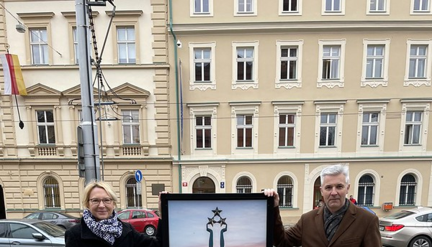 Sievietis un vīrietis pie plakāta ar brīvības pieminekļa attēlu