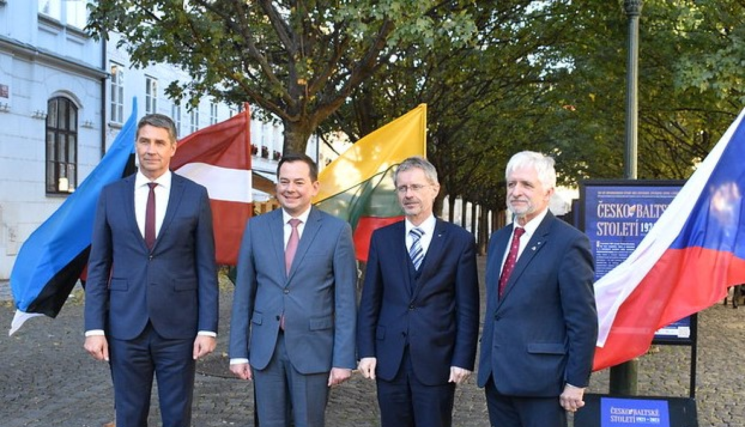 Četri vīrieši uz četru valstu karogu fona