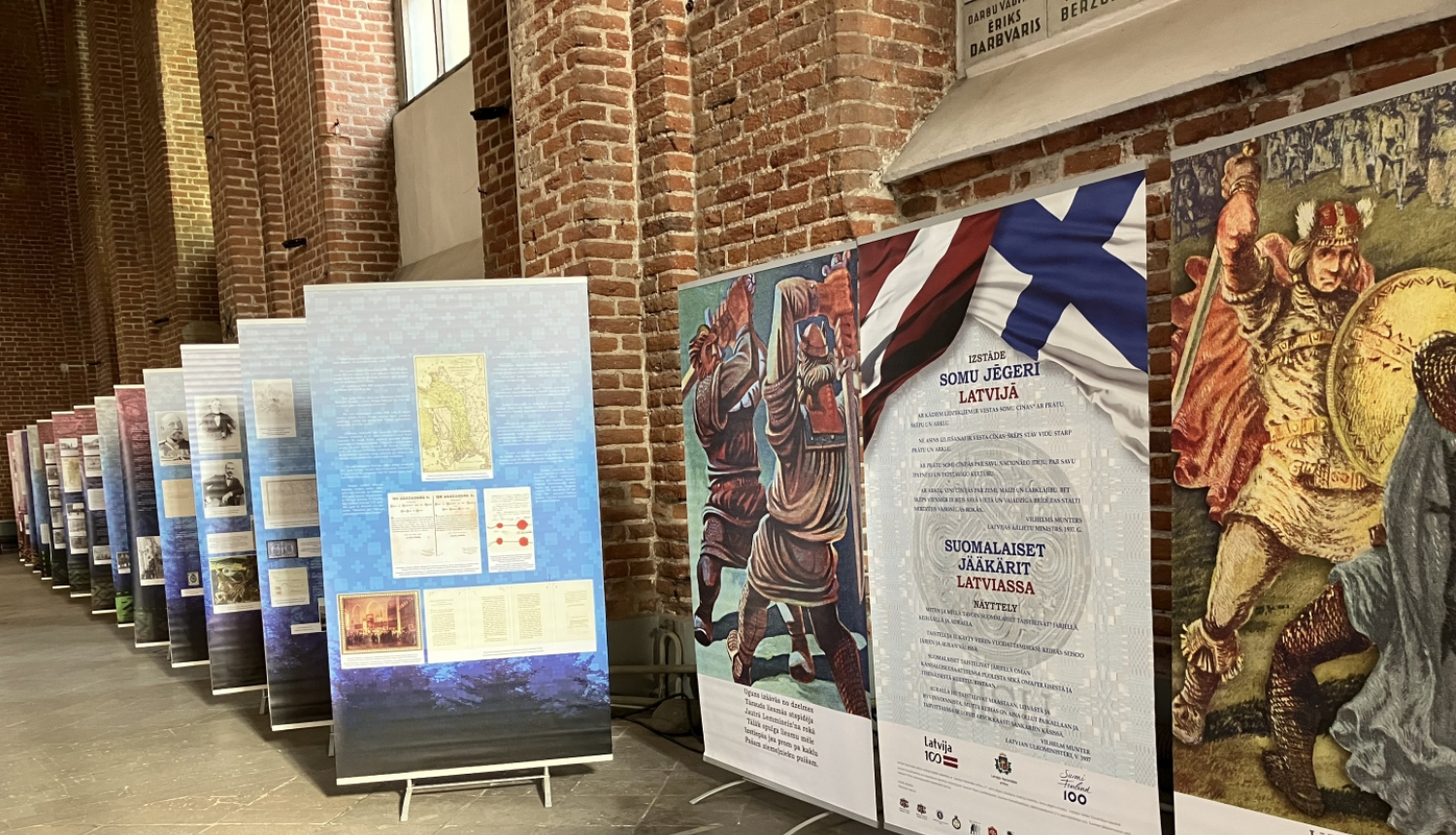 Krāsaina bilde, izstādes stendu rinda un izstādes atklāšanas stendi gar Pēterbaznīcas sienu