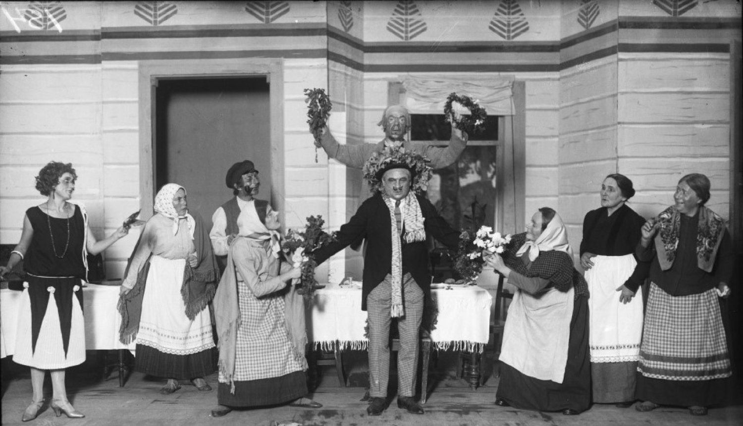 Melnbalta bilde, Aina no A. Saulīša komēdijas “Inteliģenti” uzveduma Nacionālā teātra aktieru izpildījumā. No kreisās: 1. Anta Klints - Adelīnas lomā, 6. Alfrēds Amtmanis-Briedītis - Fēliksa Šmigas lomā, 8. Berta Rūmniece - Vēsmiņas mātes lomā, 9. Ella Jēkobsone - Salmienes lomā. Rīga, 1925.gads. Autors nav zināms. Latvijas Valsts kinofotofonodokumentu arhīvs