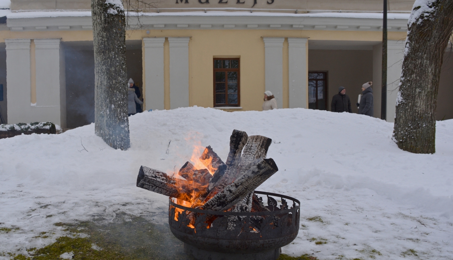 Krāsaina bilde, Balvu muzeja ēka fonā, priekšplāna degošs uzgunskurs