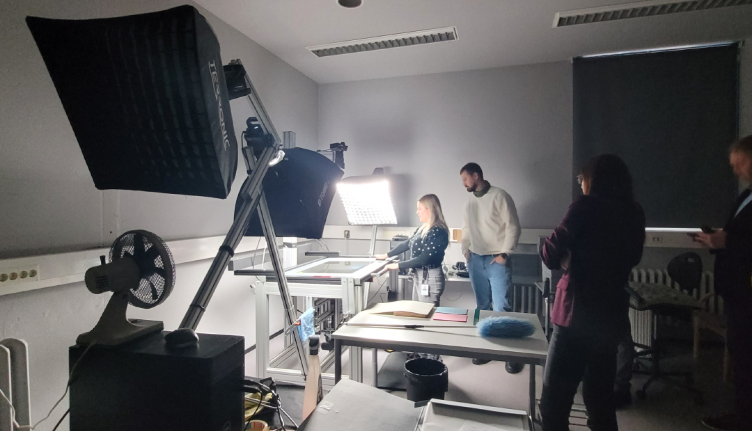 Krāsaina bilde, digitalizācijas galds ar lampām un darbiniekiem