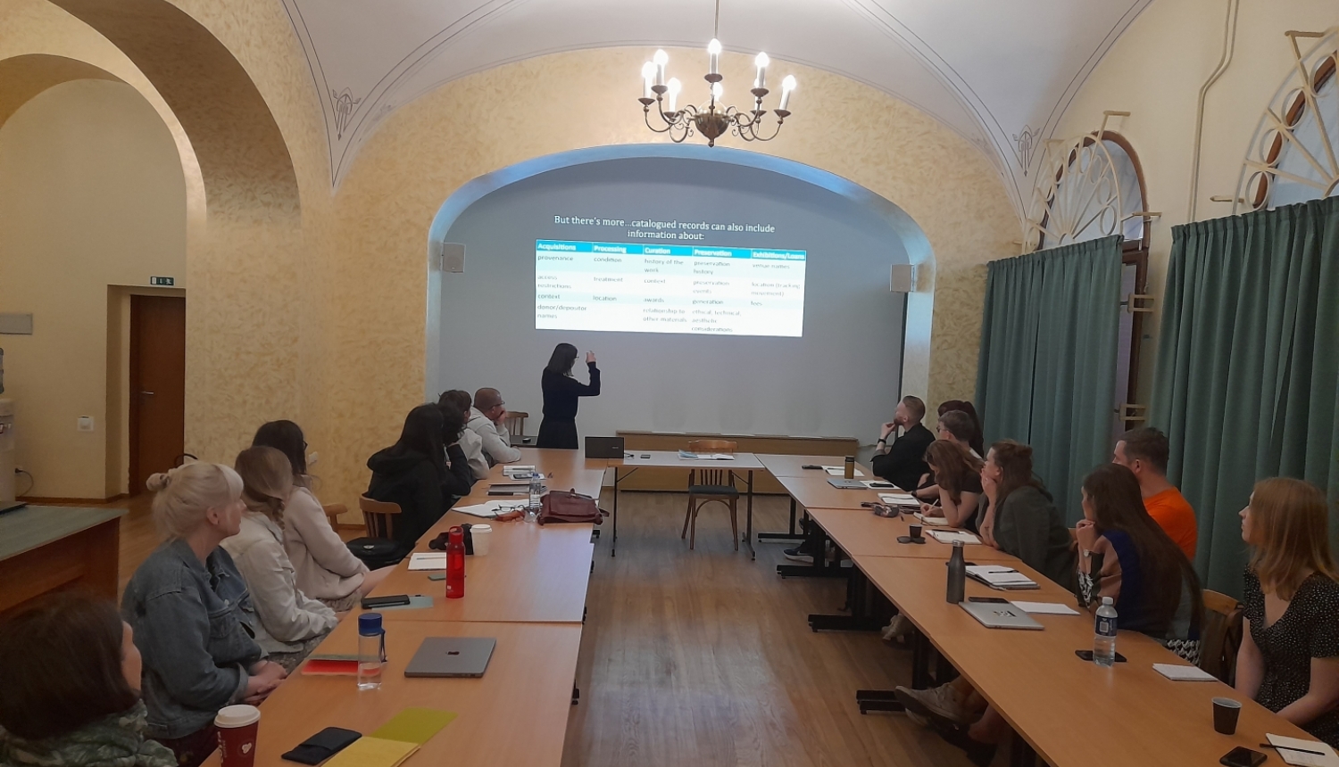 Krāsaina bilde, īskursa apmācības LNA administrācijas lielajā zālē, ekrānā prezentācija, pie galdiem sēž kursa dalībnieki