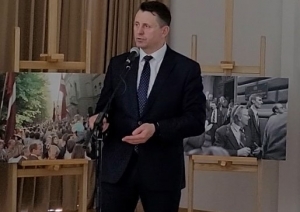 Krāsaina bilde, Balvu novada pašvaldības domes priekšsēdētājs Sergejs Maksimovs atklāj izstādi, fonā izstādes stendi